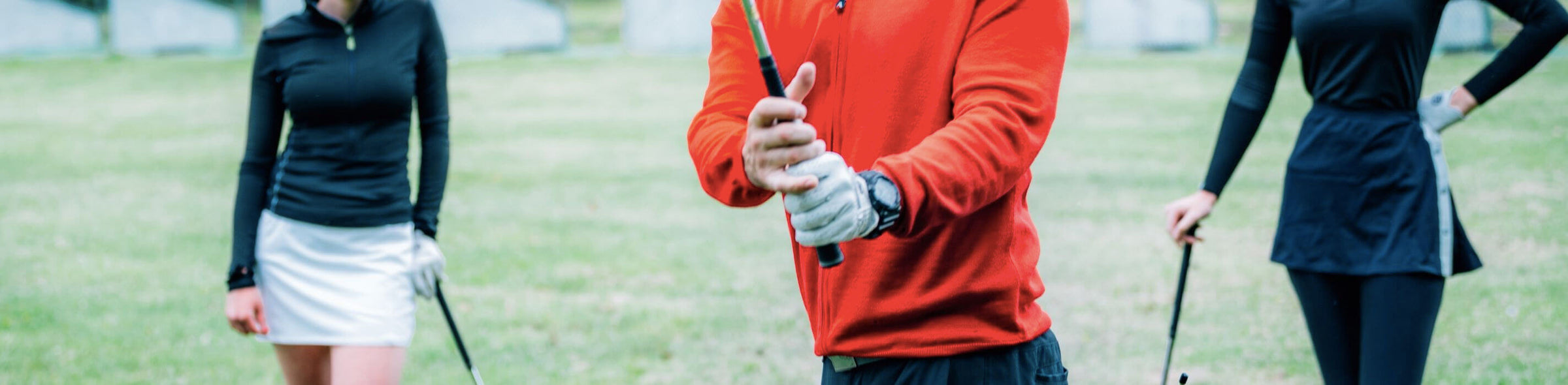 3 golfers wearing sweaters playing golf